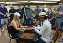 Kim Squires of Squire Cigars inspects a leaf of tobacco with Klaas Kelner.